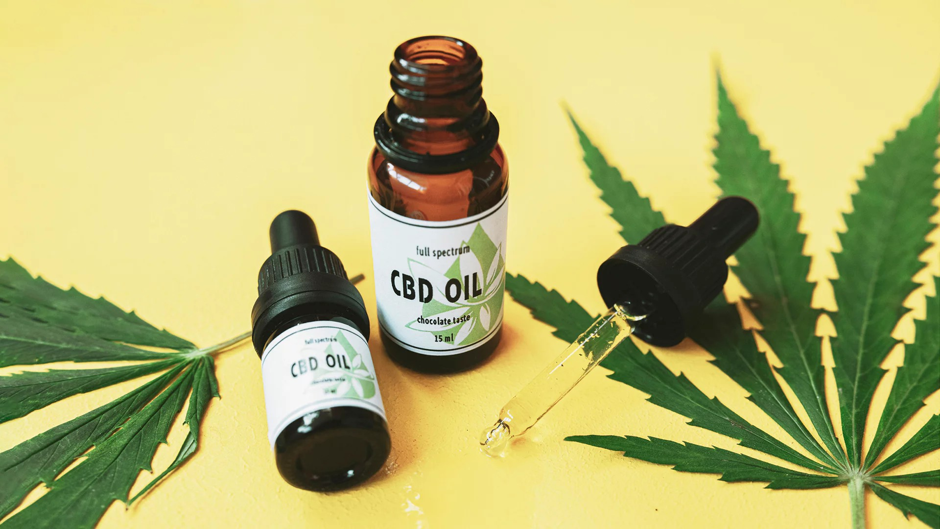 Zwei Gläsfläschchen mit CBD Öl und zwei Cannabis-Blätter