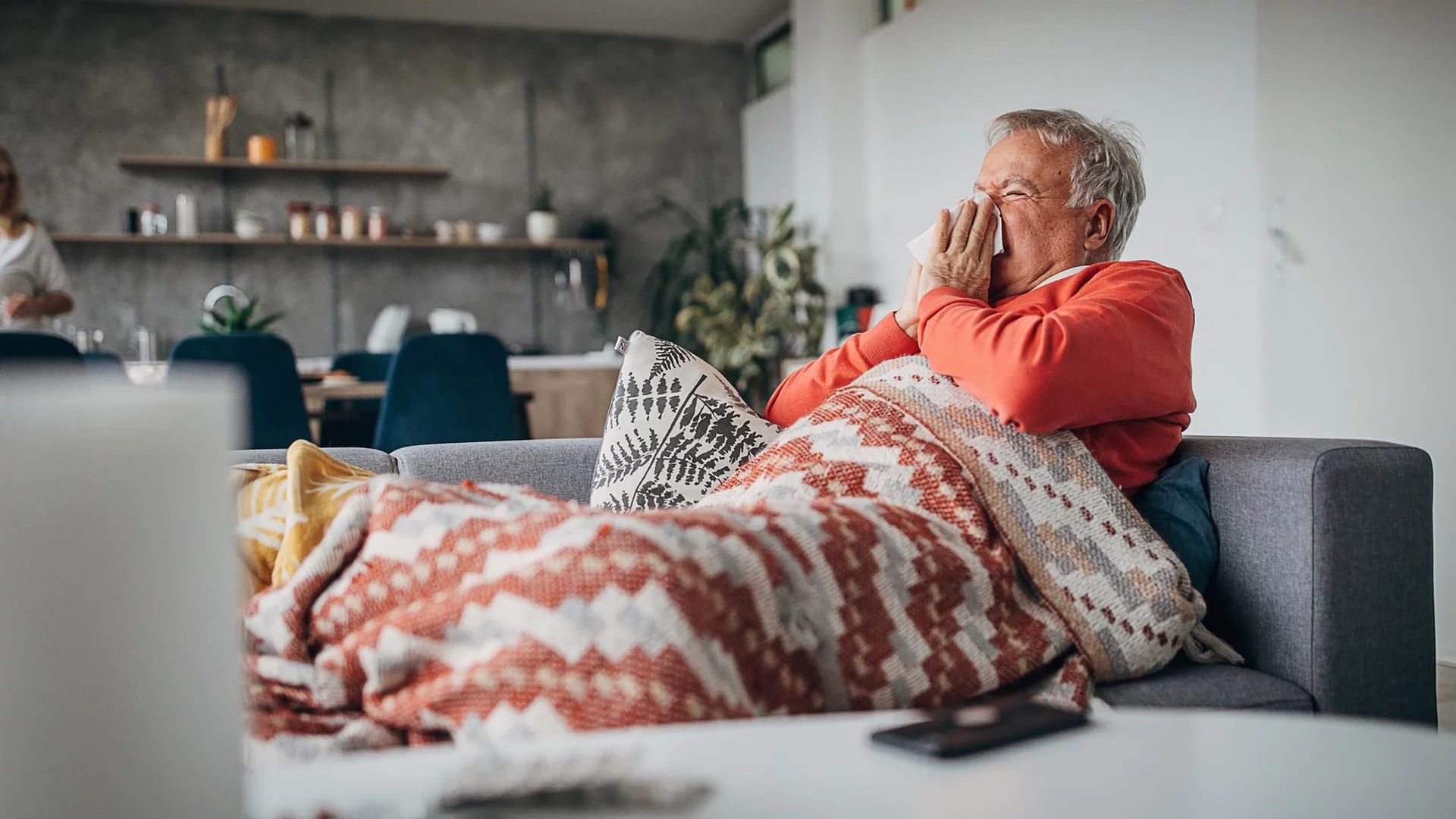 Mensch im Bett putzt sich die Nase