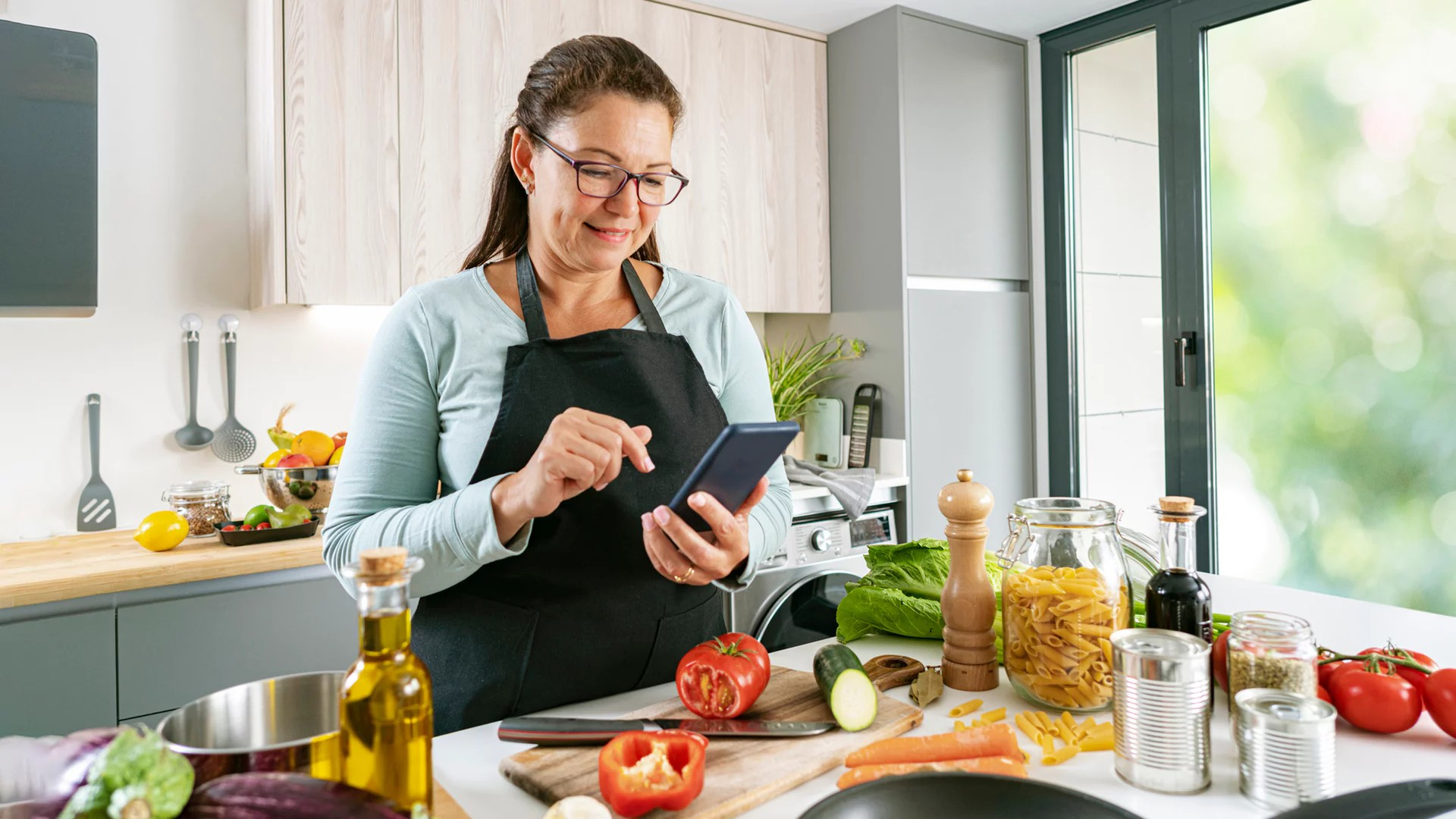 Frau beim Kochen mit Handy in der Hand