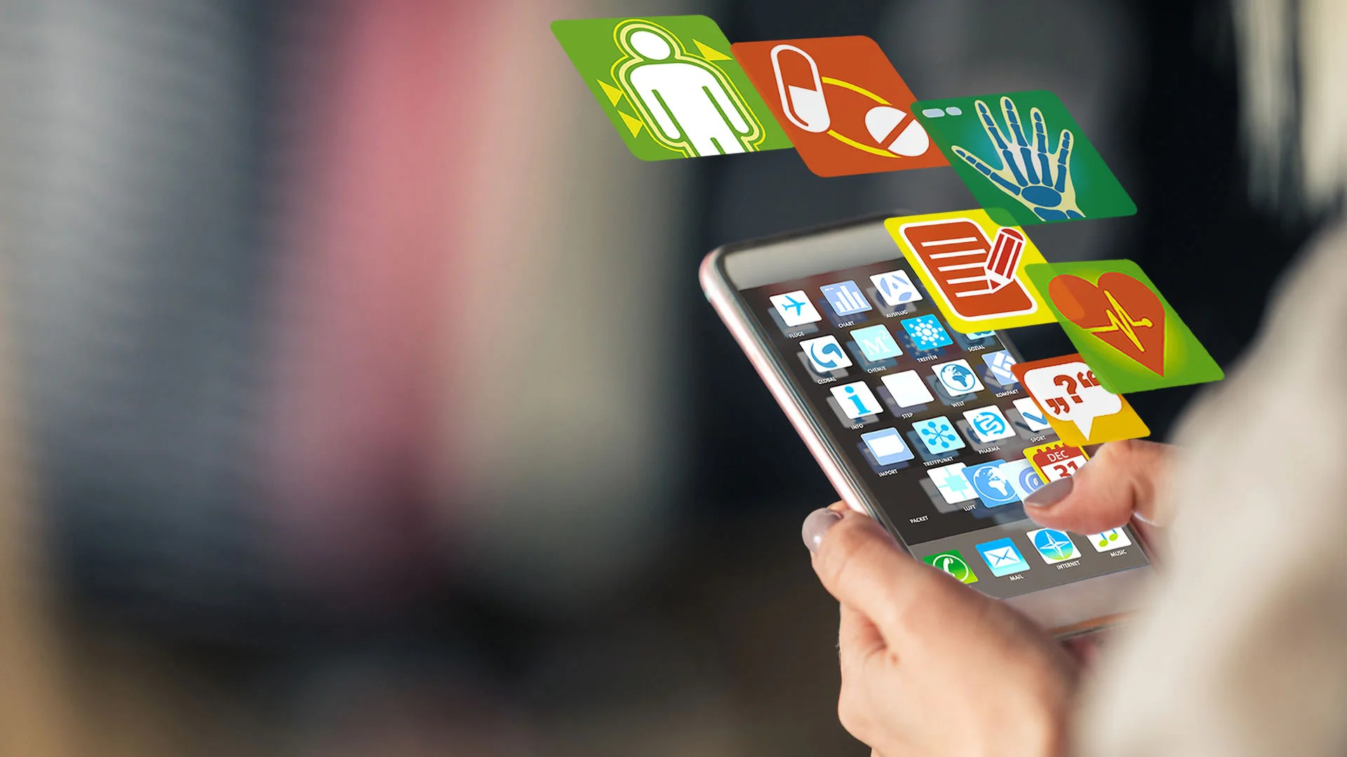 Fotografie zeigt Hände, die Smartphone mit zahlreichen bunten Gesundheits- und Medizin-Icons bedienen, die aus Bildschirm zu schweben scheinen.