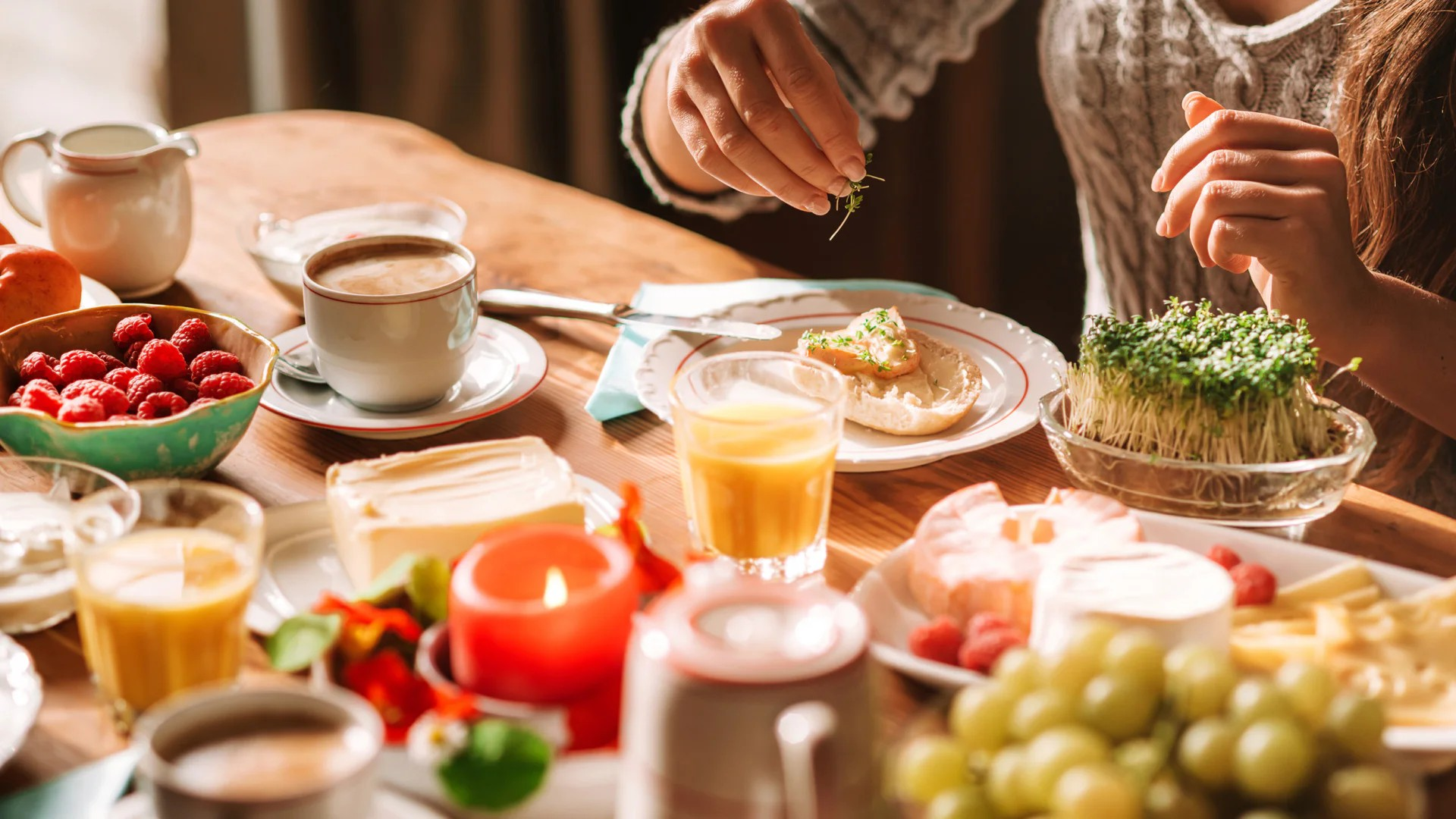 Fotografie eines reich gedeckten Frühstücks- oder Brunch-Tisches mit Kaffee, Tee, Säften, Beeren, Trauben, Gebäck, Eiern und Kräutern.